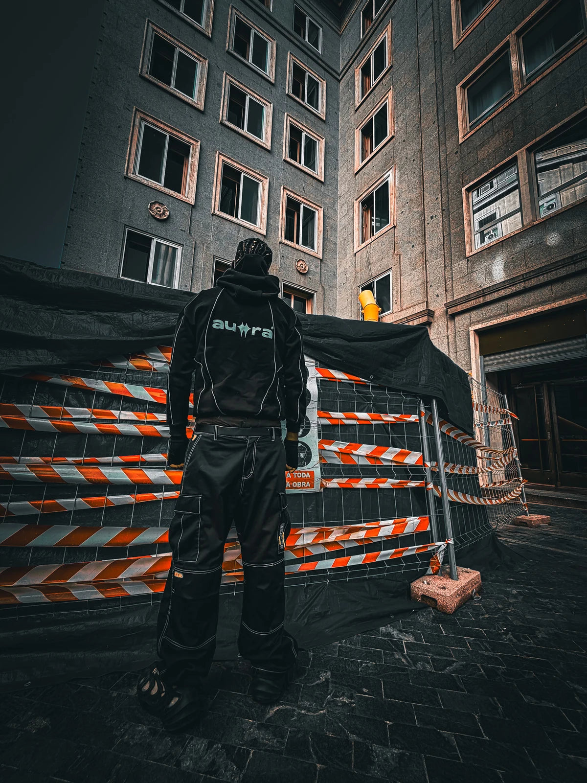 The original Phantom Armor hooded jacket worn from the back in a city courtyard